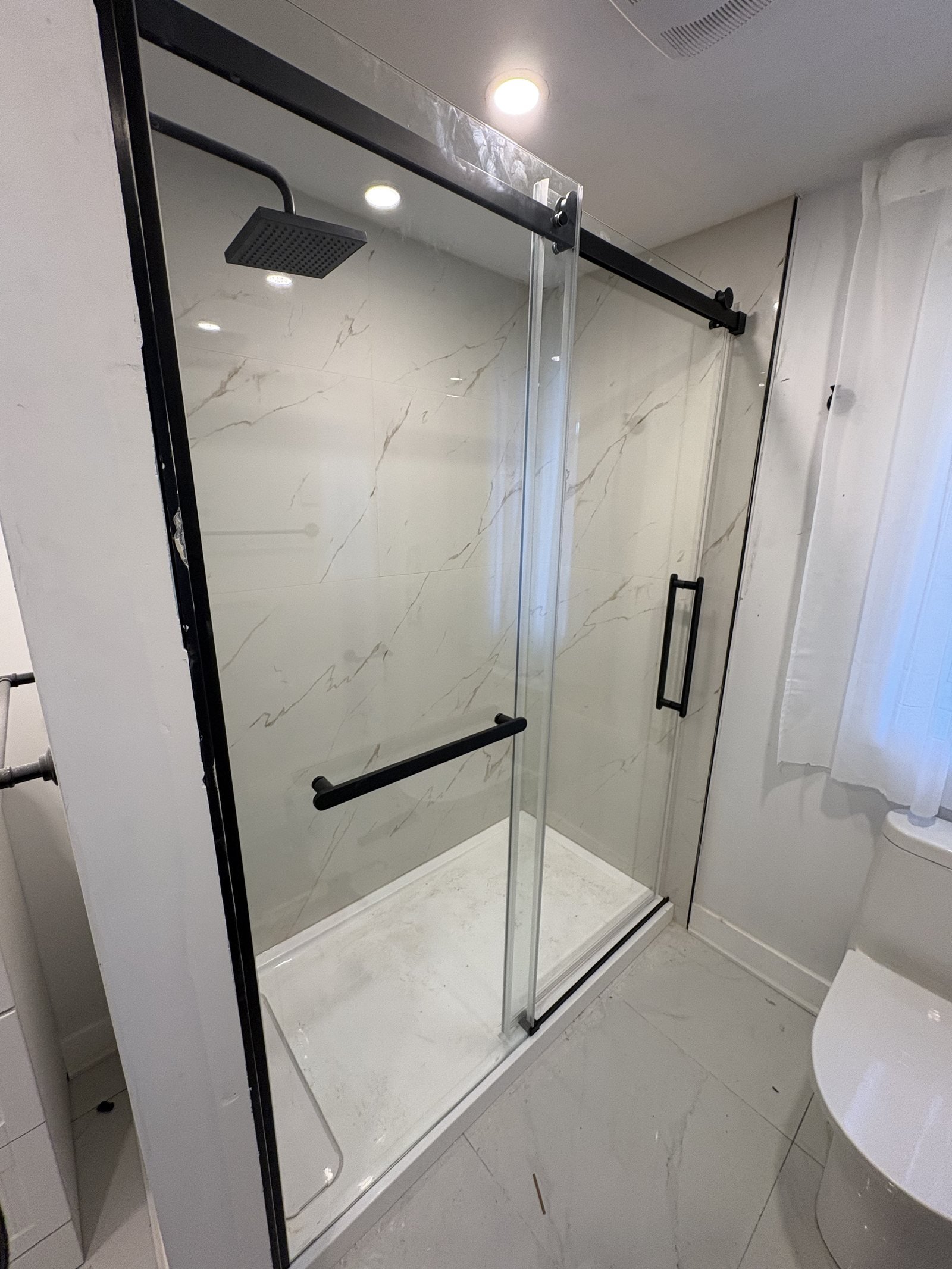 Douche moderne avec porte vitrée noire et céramique effet marbre
